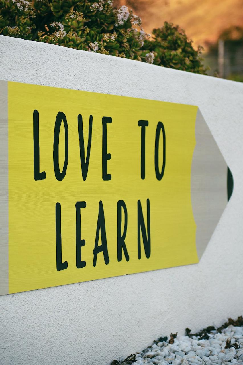 love to learn pencil signage on wall near walking man