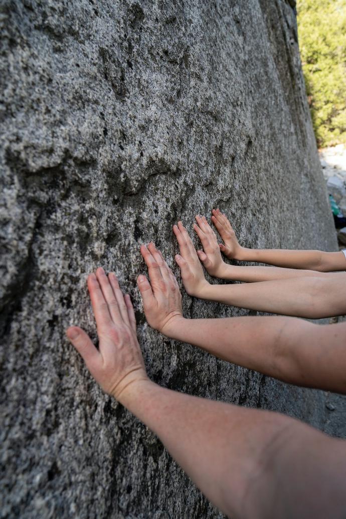 a group of people reaching up against a rock